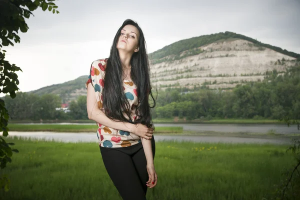 Portret van een mooie jonge vrouw op de achtergrond van de heuvel — Stockfoto