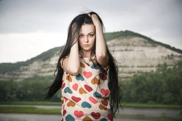 Portrait of a beautiful young woman on the background of the hill — Stock Photo, Image