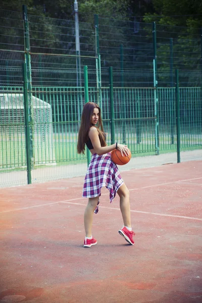 Красивая молодая женщина играет в баскетбол на открытом воздухе — стоковое фото