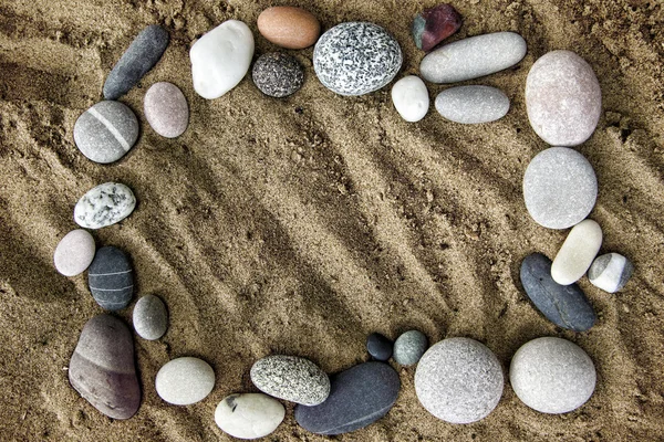 Gestell aus Steinen auf einem Hintergrund aus Sand Nahaufnahme — Stockfoto