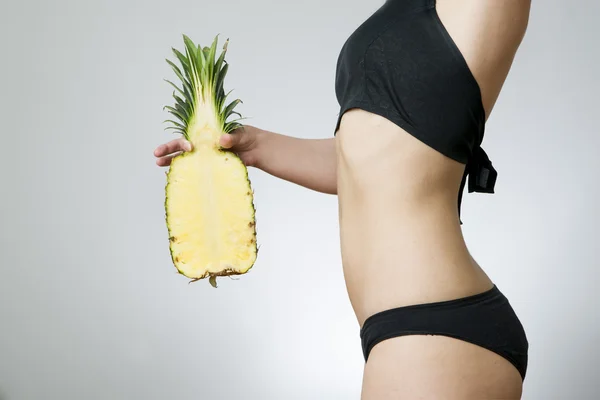 Ung kvinnas kropp med ananas — Stockfoto