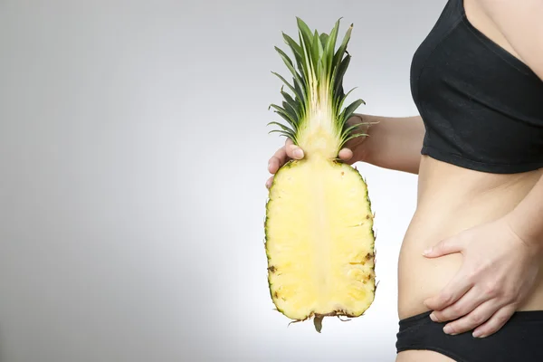 Ung kvinnas kropp med ananas — Stockfoto