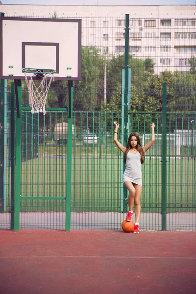 Mooie jonge vrouw spelen basketbal buitenshuis — Stockfoto