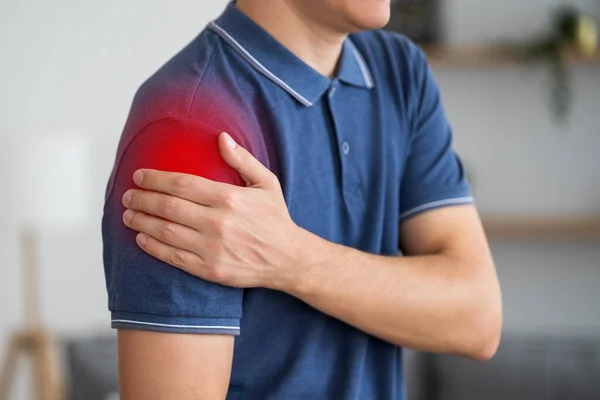 Man with pain in shoulder at home, health problems concept