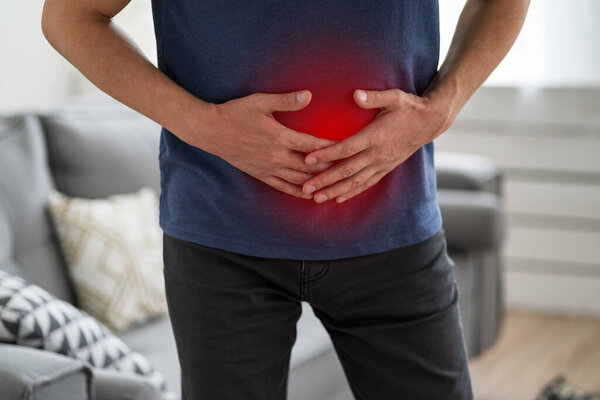 Stomach ache, man with abdominal pain suffering at home, painful area highlighted in red