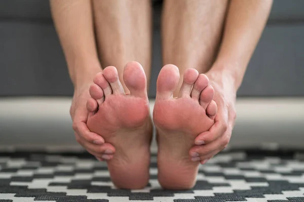 Foot pain, man suffering from feet ache at home, podiatry concept