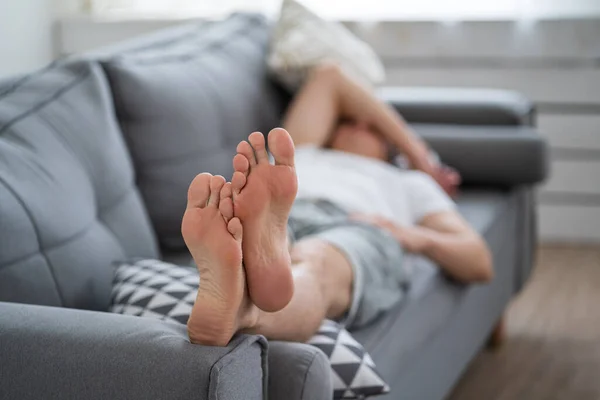 Tired man resting after work at home, male feet, body care concept at home interior