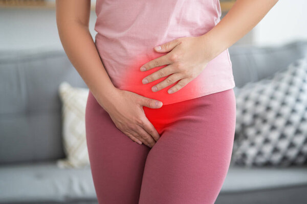 Menstrual pain, woman with stomachache suffering from pms at home, endometriosis, cystitis and other diseases of the urinary system, painful area highlighted in red