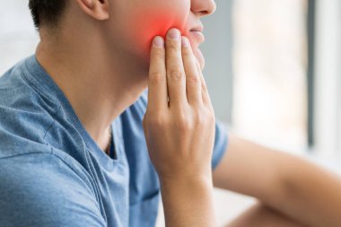 Diş ağrısı olan bir adam, yirmilik dişli periodontal bir hastalık, kırmızı ile işaretlenmiş acı verici bir bölge.