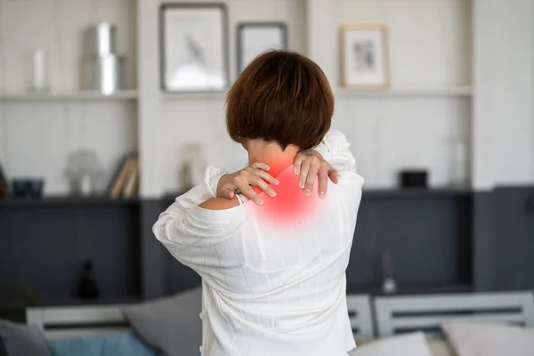 颈部疼痛 妇女在家里患背痛 疼痛区域突出显示红色 — 图库照片