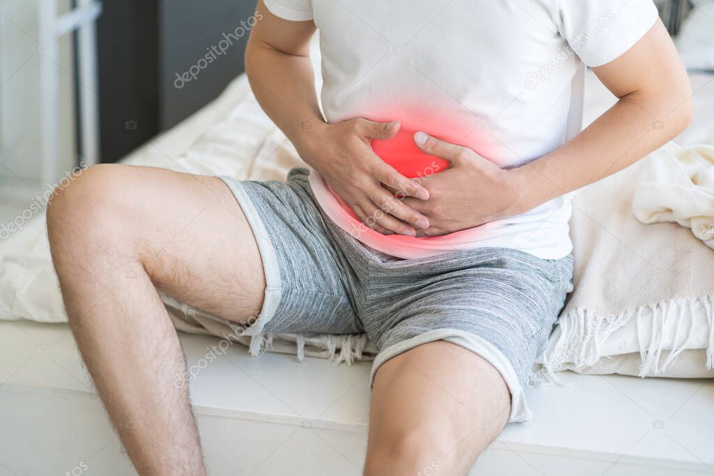 Stomach ache, man with abdominal pain suffering at home, painful area highlighted in red