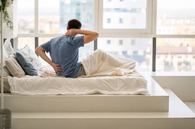 Back pain, man with backache at bedroom, health problems concept