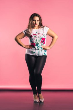 Artı, pembe arka planda günlük kıyafet modeli, vücut pozitifliği.