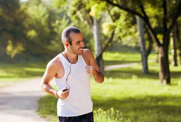 Healthy Looking Young Man Jogging in the Woods Under Morning Sun — Stockfoto