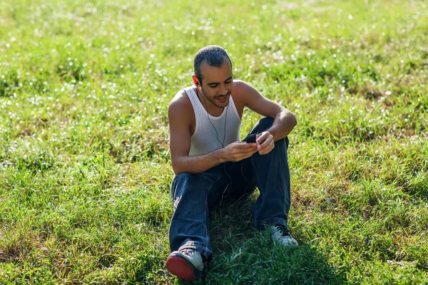 Mladý pohledný muž sedí v trávě — Stock fotografie