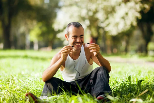 Guy listening to the player sitting on the grass — Stockfoto