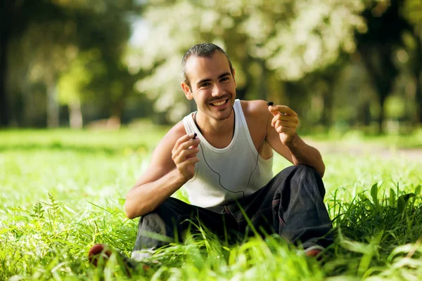 Guy listening to the player sitting on the grass — Stockfoto