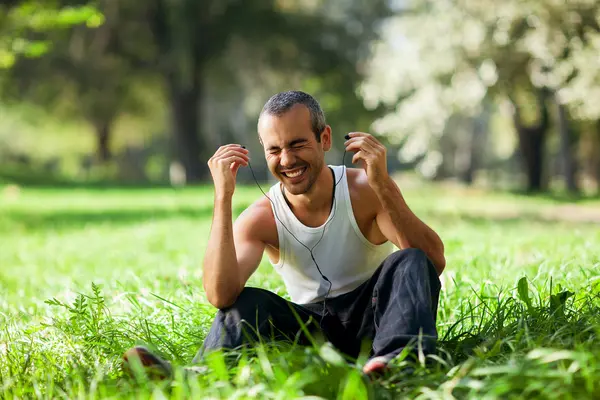 Guy listening to the player sitting on the grass — Stockfoto