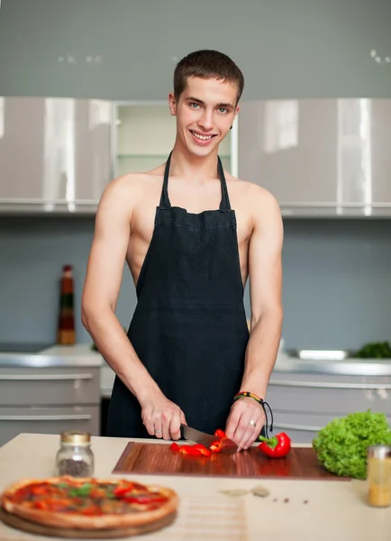 Pizza chef sexy prepara uma pizza na cozinha usando um avental — Fotografia de Stock