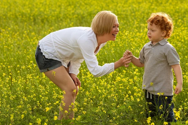 Madre e figlio si divertono. Figlio che dona fiori a sua madre — Foto Stock