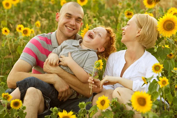 Famiglia felice divertirsi nel campo dei girasoli. Padre abbraccia suo figlio . — Foto Stock