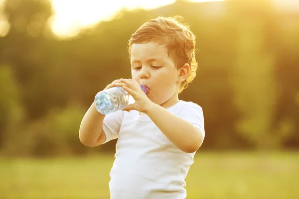 Babyjongen met bruin haar drinkwater Stockfoto