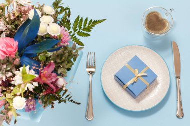 Çatal, bıçak ve bir fincan kahveyle bir tepside hediye kutusu. Üst görünüm.