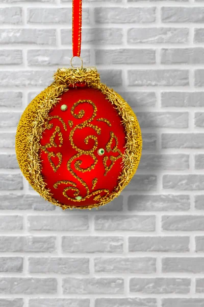 Red Christmas ball with ribbon and a wall on the background. — Stock Photo, Image