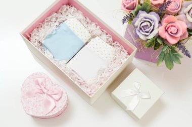 Beyaz arka planda suni çiçekler olan bir kutuda katlanmış pamuk külotlar. Kadın iç çamaşırı seti. Üst görünüm.