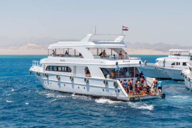 SHARM EL SHEIKH, EGYPT - 7 Haziran 2021: Sharm El Sheikh, Mısır 'da Kızıldeniz körfezinde turistlerle lüks yatlar. Bazı turistler zengin sualtı dünyasıyla mercan resiflerini görmek için şnorkelle yüzüyor.