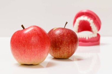 Arkaplanda insan çenesinin yerleşimi olan elmalar.