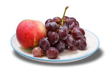 Bir demet yeşil üzüm ve beyaz arka planlı bir tabakta bir elma. Üst görünüm.