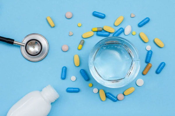 Frasco Blanco Con Diferentes Píldoras Fonendoscopio Vaso Agua Sobre Fondo — Foto de Stock