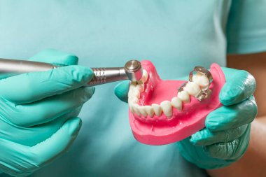 Yüksek hızlı dişçi çantası ve diş hekiminin elinde insan çenesi tasarımı var. Diş tedavisi için diş aletleri.