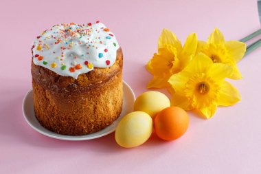 Paskalya pastası, yumurta ve nergis çiçekleri pembe arka planda..