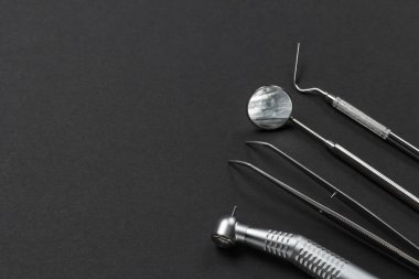 Yüksek hızlı diş macunu, cımbız, ağız aynası ve siyah arka planda fişi var. Tıbbi araçlar.