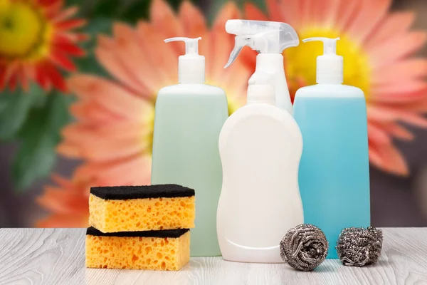 Plastic bottles of dishwashing liquid, glass and tile cleaner, detergent for microwave ovens and stoves, sponges on the blurred natural background. Washing and cleaning concept.