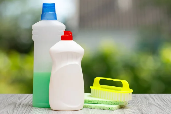 Bottles of dishwashing liquid and brush on the green background.