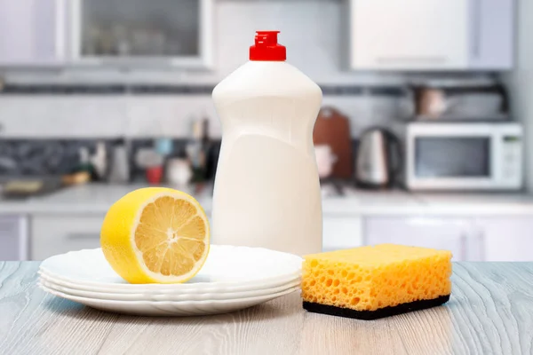 Flessen afwasmiddel, spons, borden en citroen. — Stockfoto