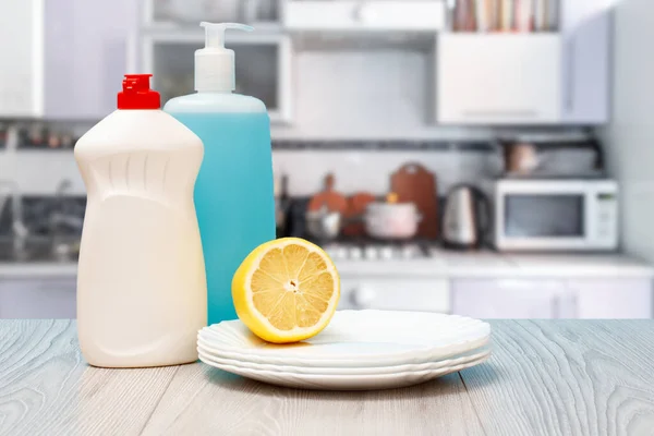 Bottles of dishwashing liquid, plates and lemon.