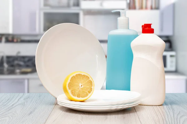 Bottles of dishwashing liquid, plates and lemon.