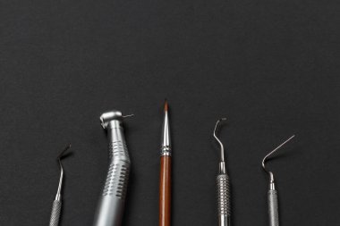 Diş macunu, fırça, küret, fiş, siyah arka planda diş yenileme aleti. Tıbbi aletler. Üst görünüm.