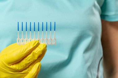 Lateks eldivenli, kürdan fırçalı bir elin yakın plan görüntüsü..