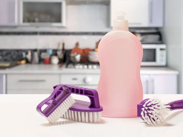 Bottle of dishwashing liquid and brushes in the kitchen. Washing and cleaning concept.