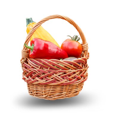 Just picked zucchini, tomato and bell pepper in a wicker basket on the white isolated background. Just harvested vegetables.