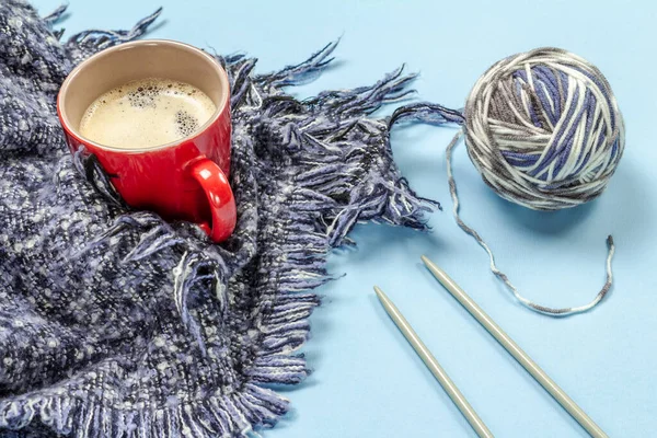 Knitting yarn ball, metal knitting needles and a cup of coffee on the blue background. Knitting concept. Top view.