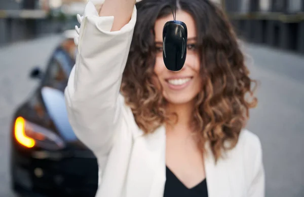 Female saleswoman holding electronic car key as corporate advertising