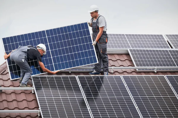 Mann montiert Solarzellen auf Hausdach. — Stockfoto