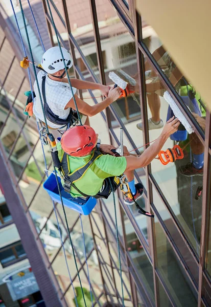 Endüstriyel dağcılık işçisi binanın penceresini temizliyor..