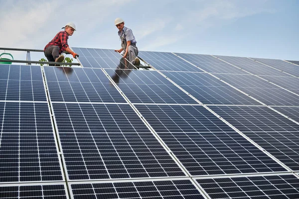 Travailleurs masculins installant un panneau solaire sur la construction métallique. — Photo